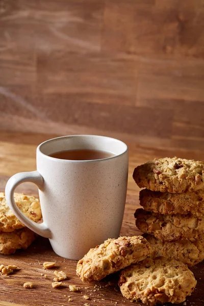 Beyaz porselen kupa çay ve tatlı kurabiye ahşap arka plan, üstten görünüm, seçici odak