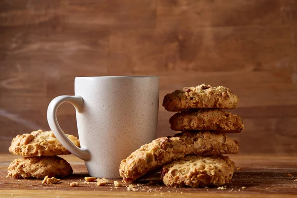 Beyaz porselen kupa çay ve tatlı kurabiye ahşap arka plan, üstten görünüm, seçici odak