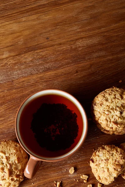 Porcelain cup of tea and sweet cookies on wooden background, top view, selective focus — Stock Photo, Image