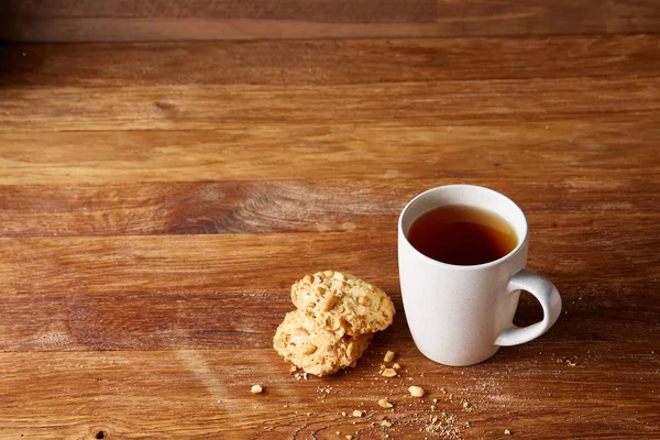 Beyaz porselen kupa çay ve tatlı kurabiye ahşap arka plan, üstten görünüm, seçici odak