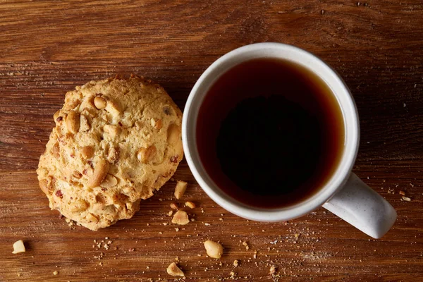 Κούπα πορσελάνη λευκό τσάι και γλυκό cookies στον ξύλινο υπόβαθρο, το top view, επιλεκτική εστίαση — Φωτογραφία Αρχείου