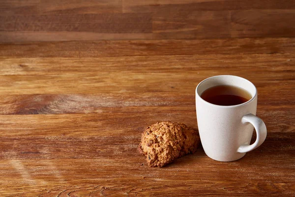 Caneca de porcelana branca de chá e biscoitos doces no fundo de madeira, vista superior, foco seletivo — Fotografia de Stock