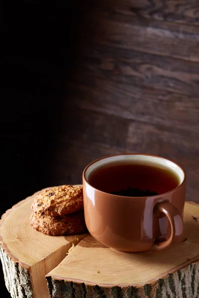 Concepto de Navidad con una taza de té caliente, galletas y decoraciones en un registro sobre fondo de madera, enfoque selectivo — Foto de Stock