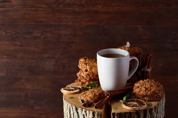Christmas concept with a cup of hot tea, cookies and decorations on a log over wooden background, selective focus — Stock Photo, Image