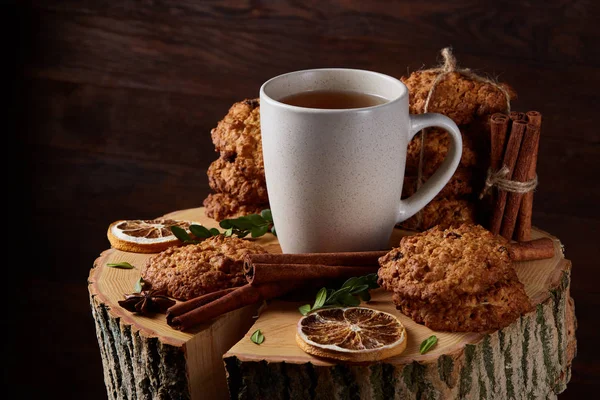 Concetto natalizio con una tazza di tè caldo, biscotti e decorazioni su uno sfondo di legno, messa a fuoco selettiva — Foto Stock