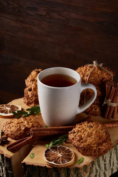 Conceito de Natal com uma xícara de chá quente, biscoitos e decorações em um log sobre fundo de madeira, foco seletivo — Fotografia de Stock