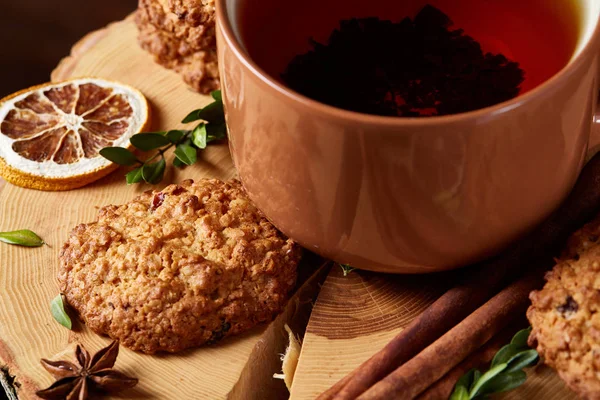 Concetto natalizio con una tazza di tè caldo, biscotti e decorazioni su uno sfondo di legno, messa a fuoco selettiva — Foto Stock