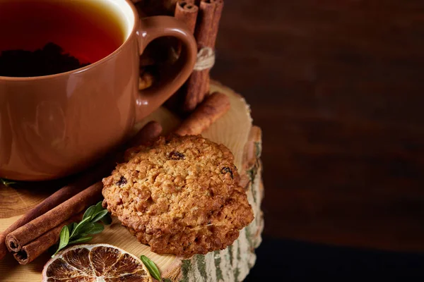 Concetto natalizio con una tazza di tè caldo, biscotti e decorazioni su uno sfondo di legno, messa a fuoco selettiva — Foto Stock