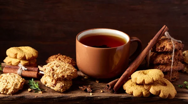 Composizione festiva concettuale con una tazza di tè caldo, biscotti e spezie su una canna di legno, messa a fuoco selettiva, primo piano — Foto Stock