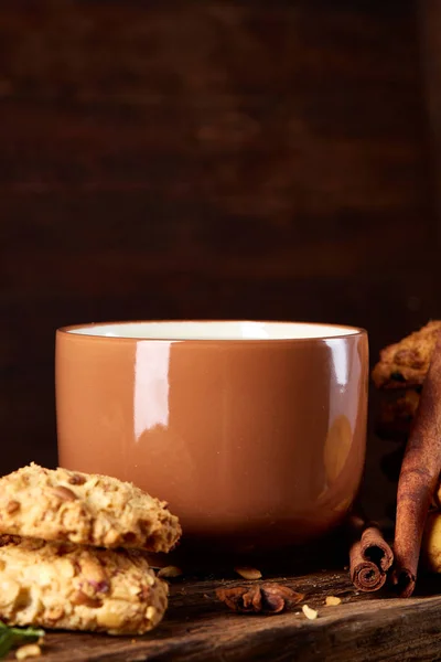 Conceptual festive composition with a cup of hot tea, cookies and spicies on a wooden barrel, selective focus, close-up