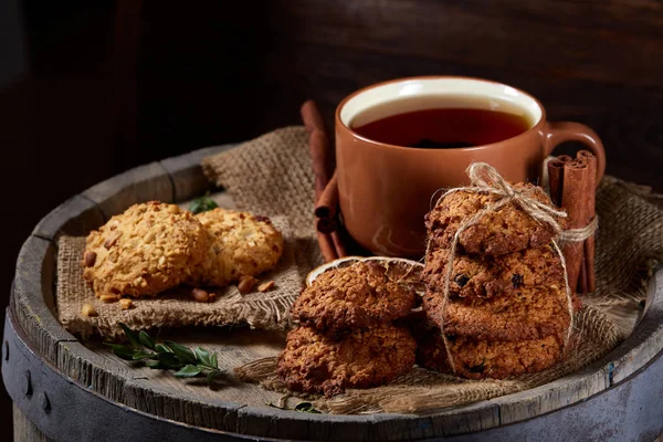 Kavramsal şenlikli bileşimi ile bir fincan sıcak çay, kurabiye ve spicies bir ahşap varil, seçici odak, yakın çekim