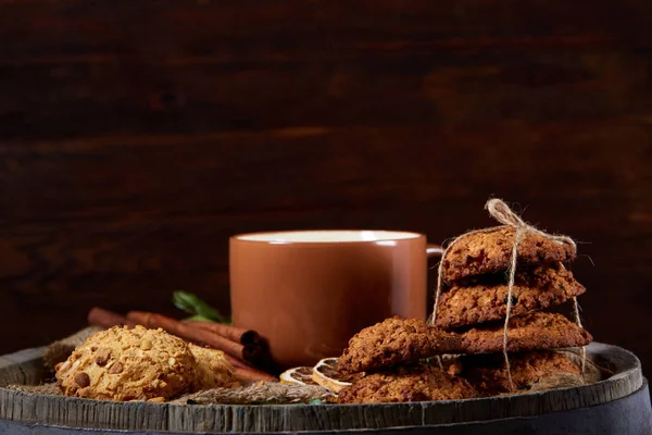 Kavramsal şenlikli bileşimi ile bir fincan sıcak çay, kurabiye ve spicies bir ahşap varil, seçici odak, yakın çekim