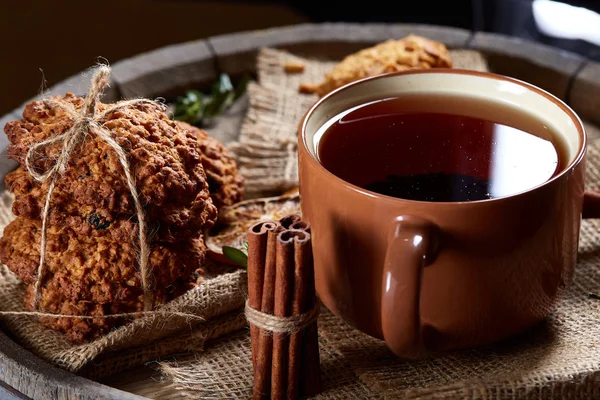 Kavramsal şenlikli bileşimi ile bir fincan sıcak çay, kurabiye ve spicies bir ahşap varil, seçici odak, yakın çekim