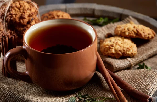 Kavramsal şenlikli bileşimi ile bir fincan sıcak çay, kurabiye ve spicies bir ahşap varil, seçici odak, yakın çekim