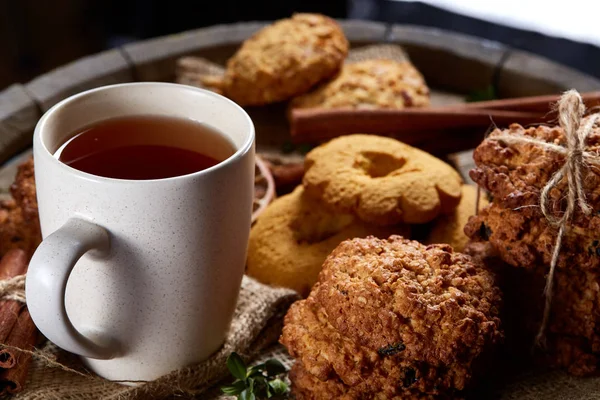 Kavramsal şenlikli bileşimi ile bir fincan sıcak çay, kurabiye ve spicies bir ahşap varil, seçici odak, yakın çekim