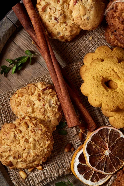 Conceptual festive composition with a cup of hot tea, cookies and spicies on a wooden barrel, selective focus, close-up