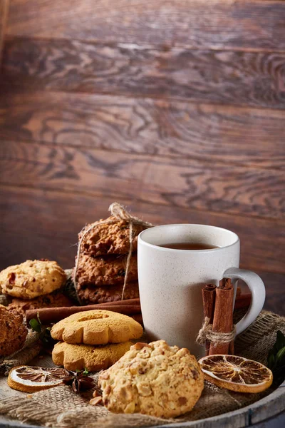 Weißer Porzellanbecher mit Tee und süßen Keksen auf Holzgrund, Draufsicht, selektiver Fokus — Stockfoto