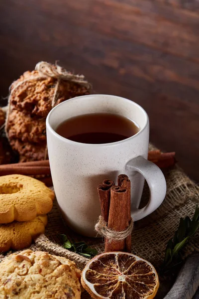 Beyaz porselen kupa çay ve tatlı kurabiye ahşap arka plan, üstten görünüm, seçici odak