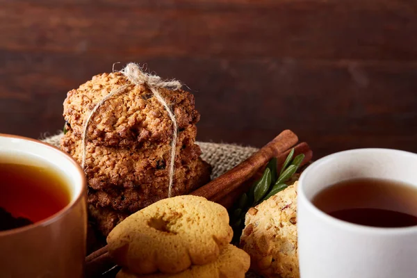 Conceito de Natal com uma xícara de chá quente, biscoitos e decorações em um log sobre fundo de madeira, foco seletivo — Fotografia de Stock