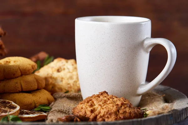 Weißer Porzellanbecher mit Tee und süßen Keksen auf Holzgrund, Draufsicht, selektiver Fokus — Stockfoto