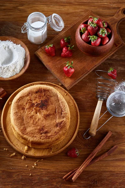 Top çilekli pasta ya da kek üzerine ahşap masa, düz yatıyordu yemek pişirmek için ham maddeler görüntüleyin. Fırın arka plan.