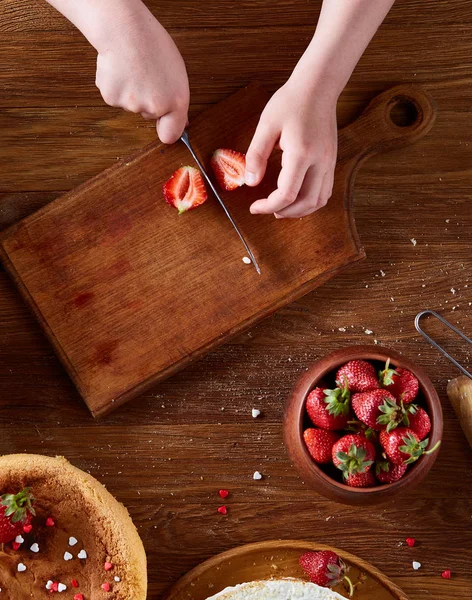 Kızlar el çilek pasta, yakın çekim, selctive odaklanmak, dikey koyarak üstten görünüm.