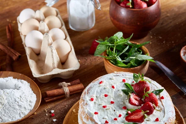 Top çilekli pasta ya da kek üzerine ahşap masa, düz yatıyordu yemek pişirmek için ham maddeler görüntüleyin. Fırın arka plan.