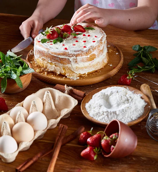 Çilek ve nane koyarak pasta, yakın çekim, selctive odak, dikey kızlar el görünümünü kırpılmış.