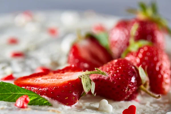 Çilek ve beyaz dokulu arka planda, seçici odak nane yaprakları ile süslenmiş krem şanti ile tart