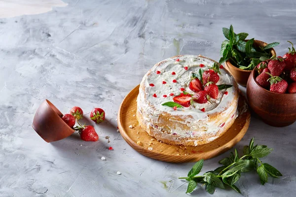 Çilek ve beyaz dokulu arka planda, seçici odak nane yaprakları ile süslenmiş krem şanti ile tart