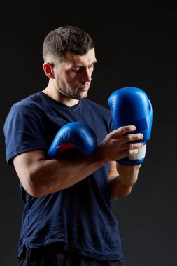 Düşük anahtar stüdyo portre yakışıklı kaslı dövüşçülerin korku koyu arka plan bulanık boks için hazırlanıyor