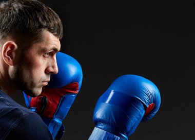 Agresif bir kaslı savaşçı, yumruğunu izole koyu arka plan üzerinde gösterilen düşük anahtar portresi kapatın.