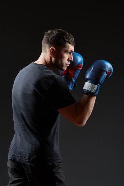 Düşük anahtar stüdyo portre yakışıklı kaslı dövüşçülerin korku koyu arka plan bulanık boks için hazırlanıyor