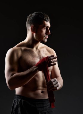 Düşük anahtar stüdyo portre yakışıklı kaslı Fighter boks koyu arka plan bulanık üzerinde pratik