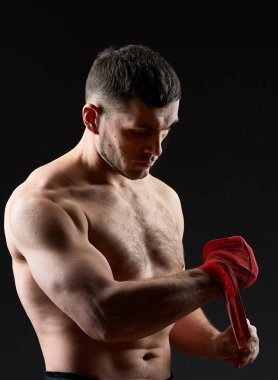 Düşük anahtar stüdyo portre yakışıklı kaslı Fighter boks koyu arka plan bulanık üzerinde pratik