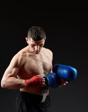 Düşük anahtar stüdyo portre yakışıklı kaslı Fighter boks koyu arka plan bulanık üzerinde pratik