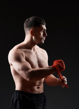 Düşük anahtar stüdyo portre yakışıklı kaslı Fighter boks koyu arka plan bulanık üzerinde pratik