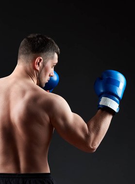 Düşük anahtar stüdyo portre yakışıklı kaslı Fighter boks koyu arka plan bulanık üzerinde pratik