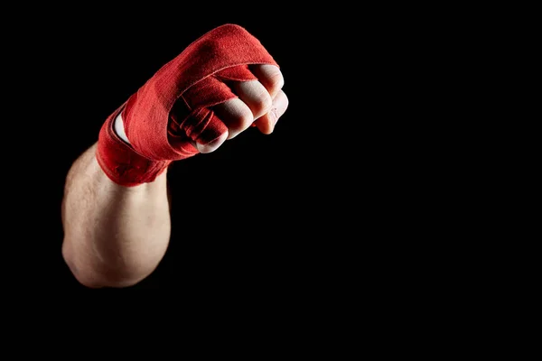 Uma bandagem vermelha boxers em sua mão isolado em fundo escuro desfocado, close-up . — Fotografia de Stock