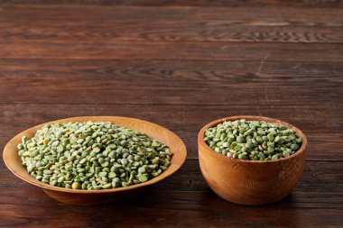 Bir kase ve plaka rustik ahşap arka plan, yakın çekim, üstten görünüm seçici odak üzerinde Besleyici yeşil bezelye.