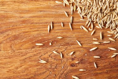 Ahşap arka plan, üstten görünüm, yakın çekim, makro, seçici odak soyulmamış yulaf taneleri yığını.