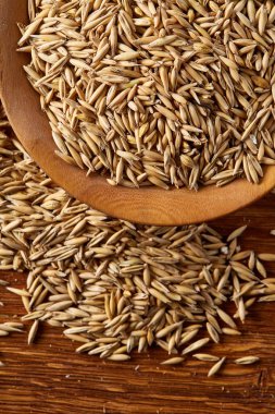 Ahşap arka plan, üstten görünüm, yakın çekim, makro, seçici odak soyulmamış yulaf taneleri yığını.