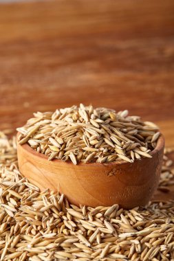 Ahşap arka plan, üstten görünüm, yakın çekim, makro, seçici odak soyulmamış yulaf taneleri yığını.