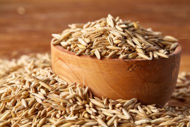 Ahşap arka plan, üstten görünüm, yakın çekim, makro, seçici odak soyulmamış yulaf taneleri yığını.