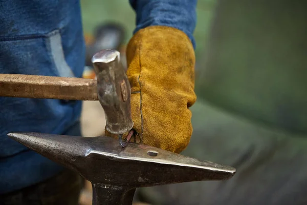 Close-up van een smeden handen manipuleren van een metalen stuk boven zijn smederij, selectieve aandacht. — Stockfoto