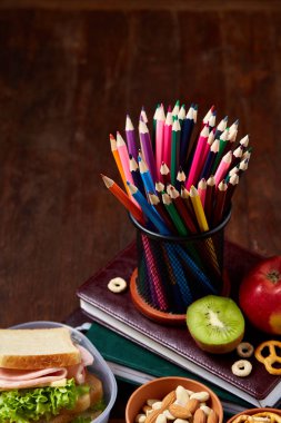 Okul öğle yemeği molası ile sağlıklı öğle yemeği kutusu ve okul malzemeleri ahşap masa, seçici odak kavramı.