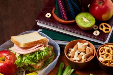 Okul öğle yemeği molası ile sağlıklı öğle yemeği kutusu ve okul malzemeleri ahşap masa, seçici odak kavramı.