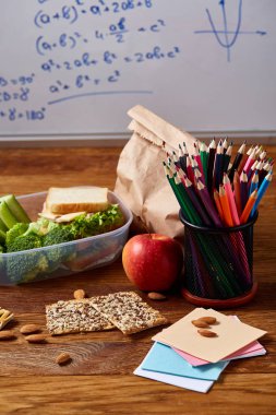 Yeşil salata ve konteyner ve okul malzemeleri, ahşap masa, seçici odak üzerinde sebze ile lezzetli öğle yemeği.