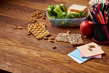 Yeşil salata ve konteyner ve okul malzemeleri, ahşap masa, seçici odak üzerinde sebze ile lezzetli öğle yemeği.