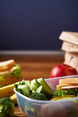 Yeşil salata ve konteyner ve okul malzemeleri, ahşap masa, seçici odak üzerinde sebze ile lezzetli öğle yemeği.